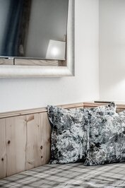 Ein gemütliches Hotelzimmer mit Holzverkleidung, gemusterten Kissen und Spiegel an der Wand.