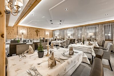 Ein elegant gedecktes Hotelrestaurant mit mehreren Tischen, warmem Holzdekor und Kerzenlicht.