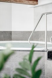 Ein runder Whirlpool mit Edelstahlhandlauf im hellen Wellnessbereich.