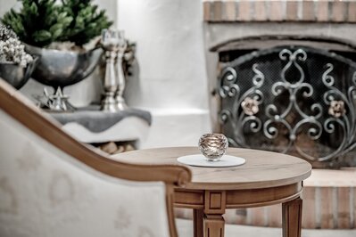 Eine elegante Lounge mit runden Tischen, Kerzenlicht und einem Kamin im Hintergrund.