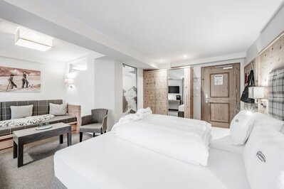 Helles Hotelzimmer mit Doppelbett, Sitzbank und Holzmöbeln im Hotel Jenewein in Obergurgl.