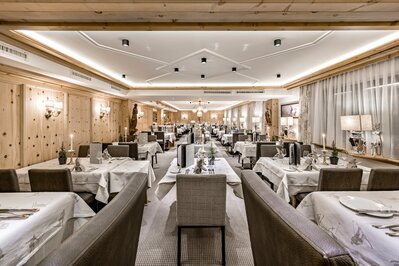 Elegantes Hotelrestaurant mit gedeckten Tischen, warmen Holzwänden und gedämpfter Beleuchtung.