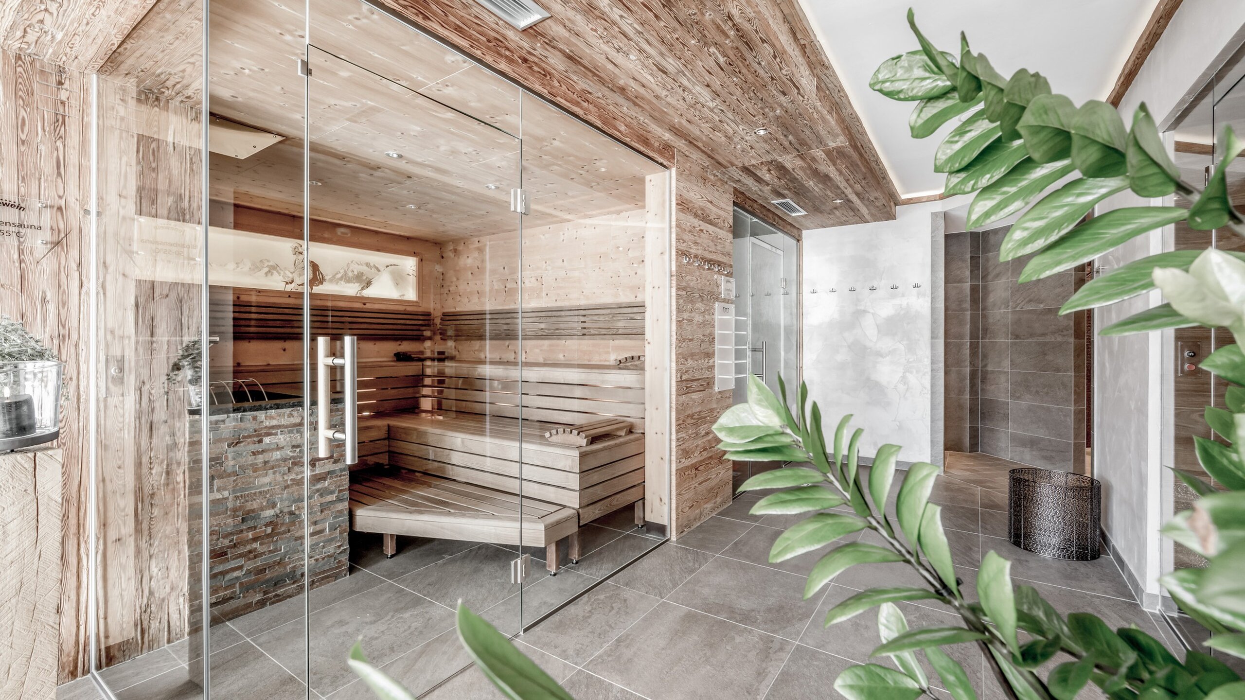 Eine helle Sauna mit Glasfront, Holzausstattung und Blick in den Ruheraum.