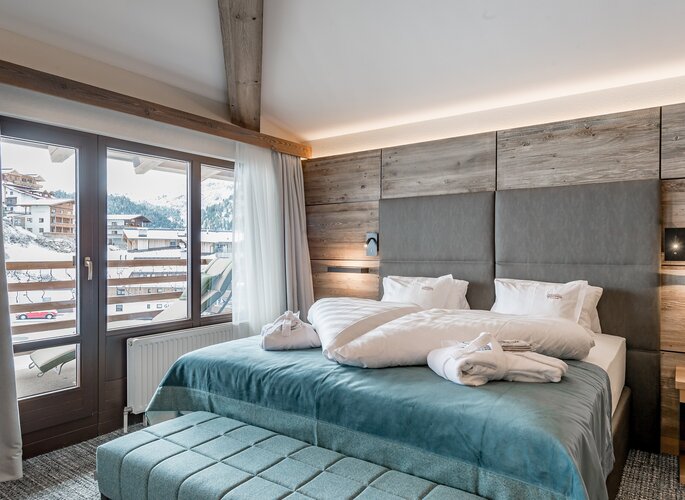 Romantikzimmer im Hotel Jenewein in Obergurgl Ein Romantikzimmer mit Doppelbett, Holzelementen und Blick auf die verschneiten Berge.
