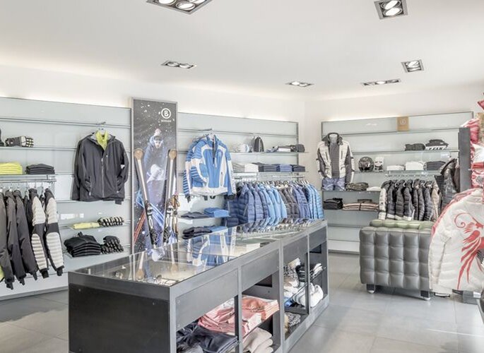 Ein heller Skiverleih mit Winterbekleidung und Skiausrüstung im Verkaufsraum.