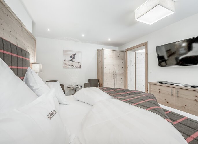 Familienzimmer im Hotel Jenewein in Obergurgl Helles Familienzimmer mit Doppelbett, Holzmöbeln und Fernseher im Hotel Jenewein.