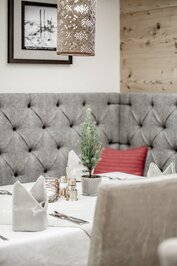 Ein gedeckter Tisch im Hotelrestaurant mit Stoffservietten, Besteck, Gewürzstreuern und kleiner Dekoration.