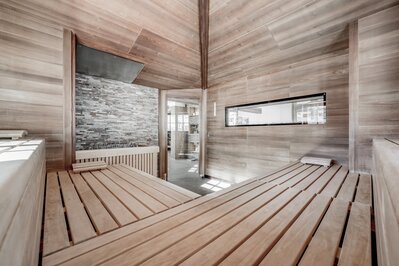 Holzsauna mit Sitzbänken und Blick in den Ruhebereich im Hotel Jenewein.