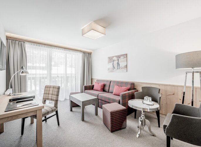 Familienzimmer im Hotel Jenewein mit Bergblick Helles Familienzimmer mit Sofa, Schreibtisch und Sitzbereich sowie Blick auf die Berge.