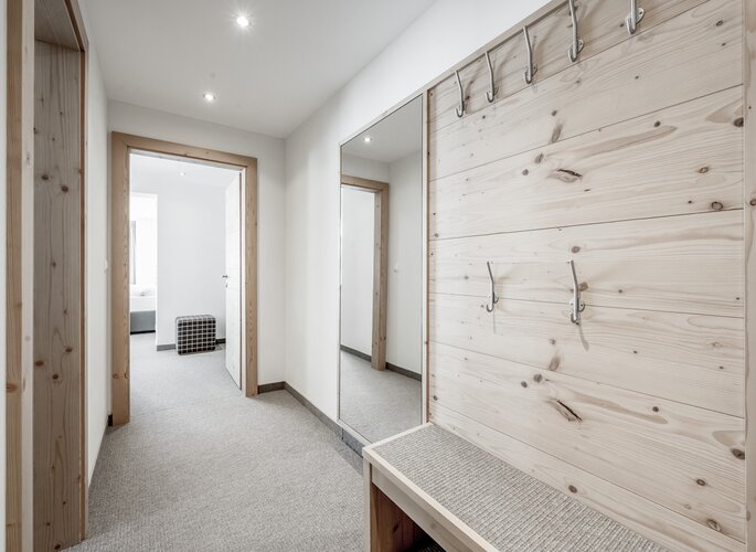 Vorraum der Turmsuite im Hotel Jenewein Heller Vorraum mit Holzdetails, Garderobenwand, Spiegel und Bank in der Turmsuite.