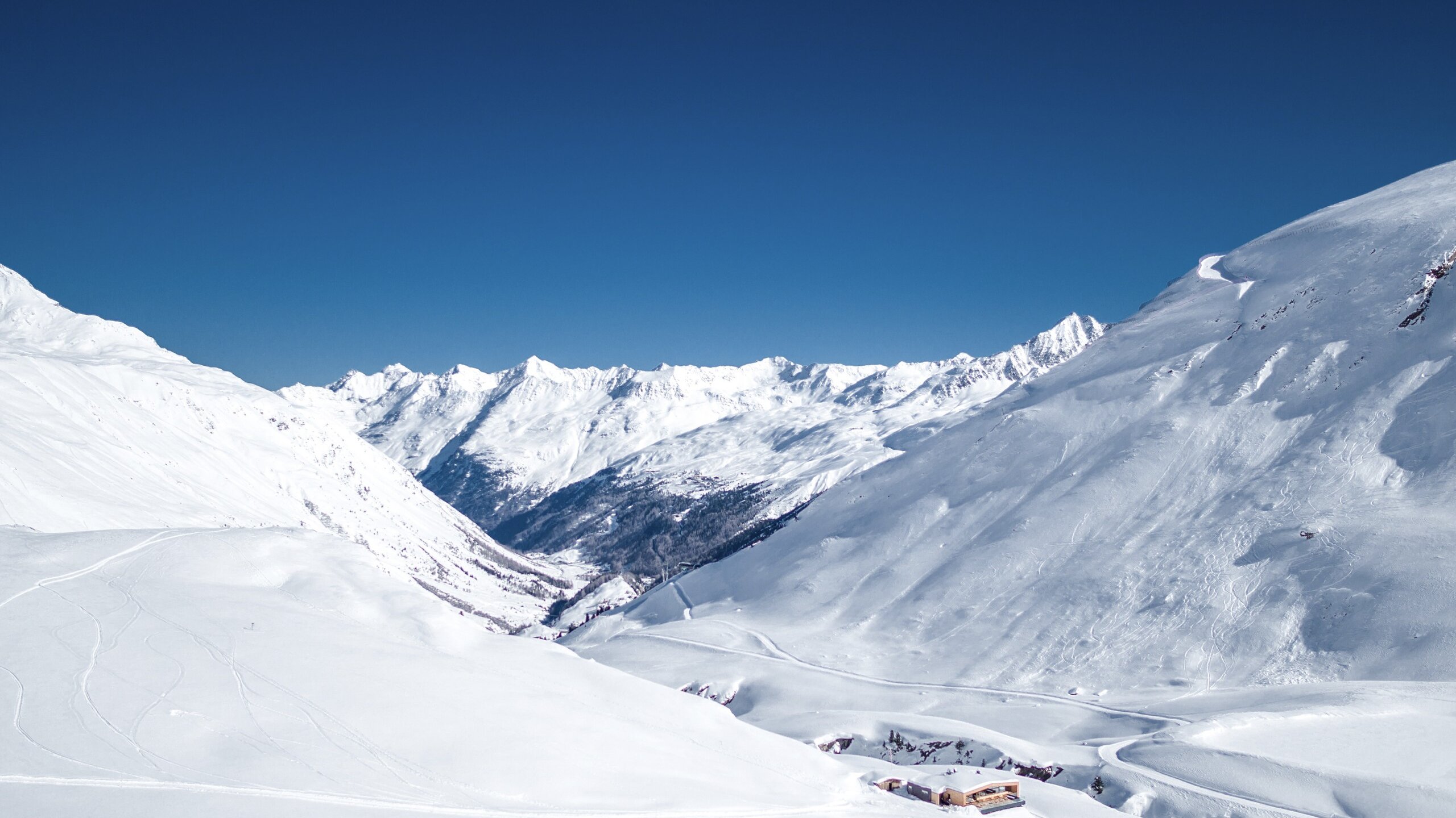 Verschneite Skipisten und Berge unter klarem blauen Himmel in Obergurgl.
