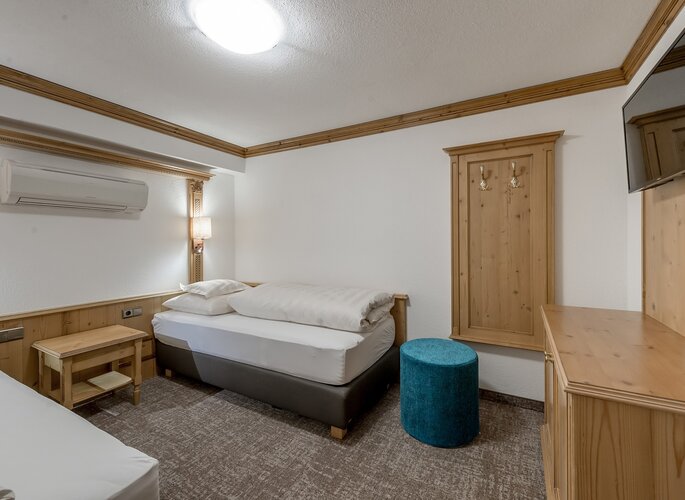 Appartement-Schlafzimmer im Landhaus Jenewein Ein schlichtes Schlafzimmer im Appartement mit zwei Betten, Holzmöbeln und Wandlampe.