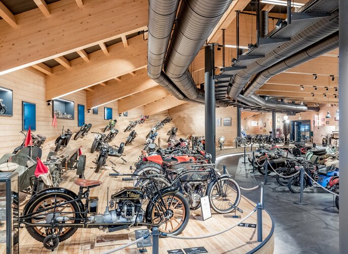 Ein heller Bike- und Motorradraum mit mehreren geparkten Rädern und Motorrädern in einem Holzraum.