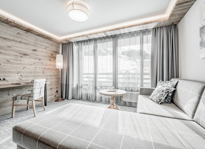 Juniorsuite im Hotel Jenewein in Obergurgl Eine helle Juniorsuite mit Sitzbereich, Schreibtisch und Blick auf die verschneiten Berge.