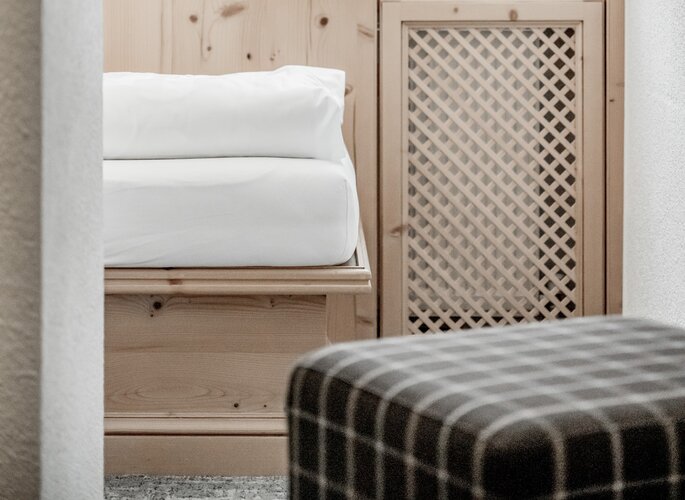 Ein Bett mit weißer Bettwäsche steht vor einer Holzverkleidung und einem Schrank mit Gittertür.