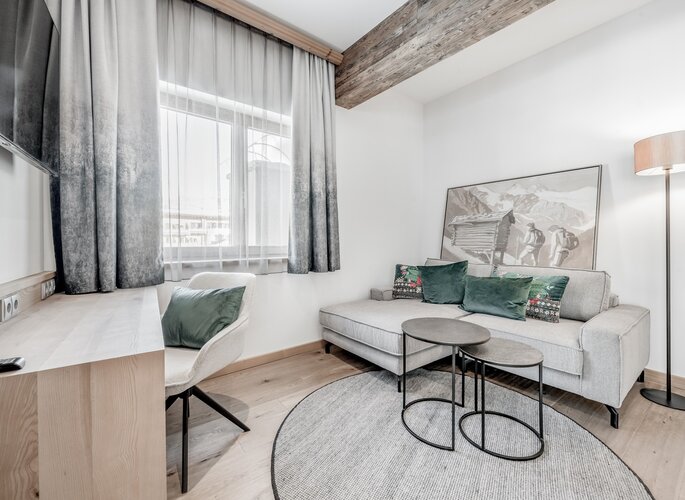 Komfortzimmer im Hotel Jenewein in Obergurgl Gemütlicher Sitzbereich im Komfortzimmer mit Sofa, Schreibtisch und großen Fenstern.