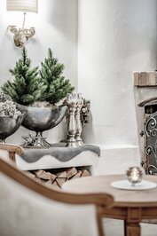 Eine winterliche Dekoration mit Tannenzweigen, Kerzenhaltern und Sternen steht vor einem Kamin.