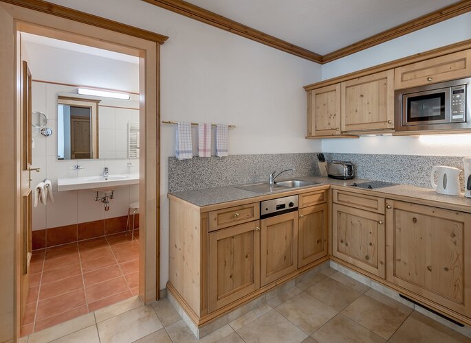Appartement mit Küche im Landhaus Jenewein Blick in die voll ausgestattete Küche des Appartements mit Holzmöbeln und angrenzendem Bad.