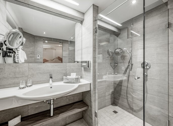 Ein modernes Badezimmer mit Waschbecken, Spiegel und Glasdusche im Hotelzimmer.