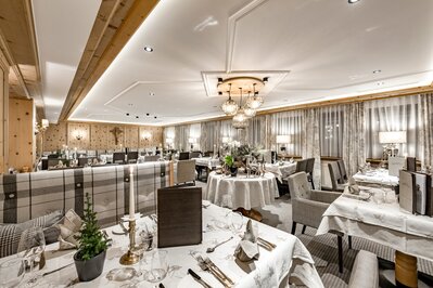 Das Hotelrestaurant ist mit gedeckten Tischen, warmem Licht und alpiner Holzvertäfelung eingerichtet.