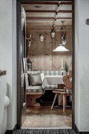 Eine gemütliche Stube mit Holzwänden, Eckbank und gedecktem Tisch im Hotel Jenewein.