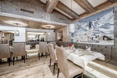 Ein stilvoll eingerichtetes Hotelrestaurant mit gedeckten Tischen und winterlicher Wandmalerei.