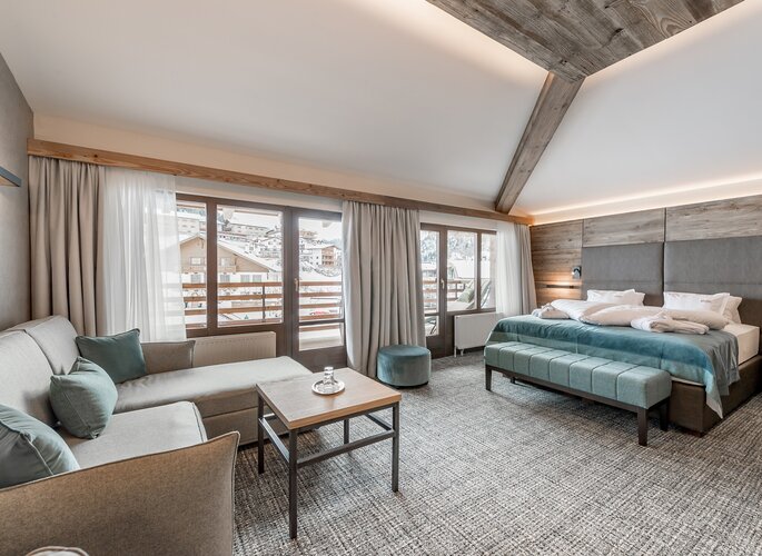 Romantikzimmer im Hotel Jenewein in Obergurgl Ein helles Romantikzimmer mit Sofa, Doppelbett und großen Fenstern mit Blick auf den Winterort.