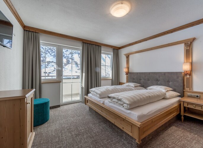 Ein Schlafzimmer im Appartement mit Doppelbett und Blick auf die verschneiten Berge.