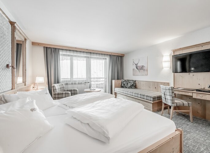Doppelzimmer mit Balkon und Bergblick in Obergurgl Ein helles Doppelzimmer mit zwei Betten, Sitzbereich, TV und Balkonblick auf die Berge.
