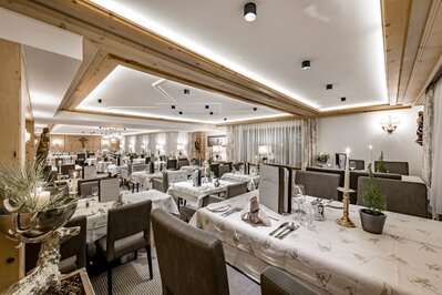 Das elegant gedeckte Hotelrestaurant zeigt eingedeckte Tische, warme Beleuchtung und viel Holz.