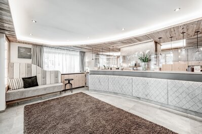 Die helle Hotelrezeption mit Sitzbank, Empfangstresen und Holzdetails im Hotel Jenewein in Obergurgl.