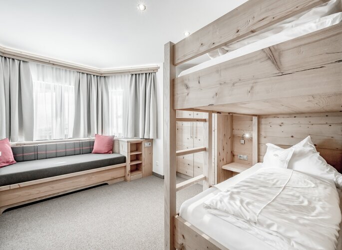 Turmsuite mit Kinderschlafzimmer in Obergurgl Ein helles Kinderschlafzimmer mit Stockbett, Sitzbank und großen Fenstern in der Turmsuite.