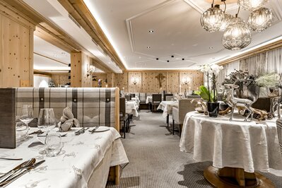 Ein elegant gedecktes Hotelrestaurant mit Holzwänden, warmem Licht und liebevoll arrangierten Tischen.