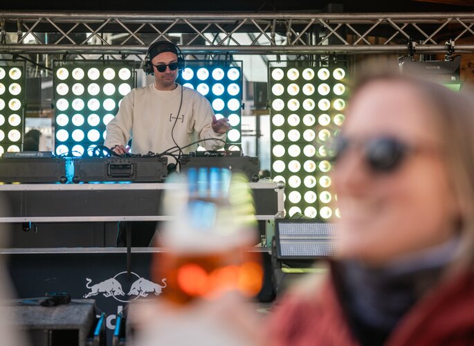 Ein DJ legt bei einer Veranstaltung in Obergurgl auf, während im Vordergrund ein Getränk unscharf zu sehen ist.