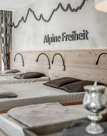 Ruheraum mit Liegen und Wanddeko im alpinen Design.