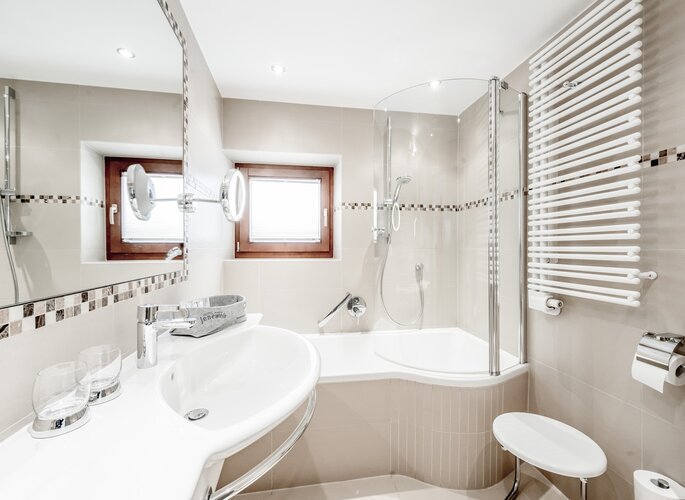 Badezimmer im Doppelzimmer im Hotel Jenewein Helles Badezimmer mit Badewanne, Dusche, Waschtisch und Handtuchheizkörper im Hotel Jenewein.