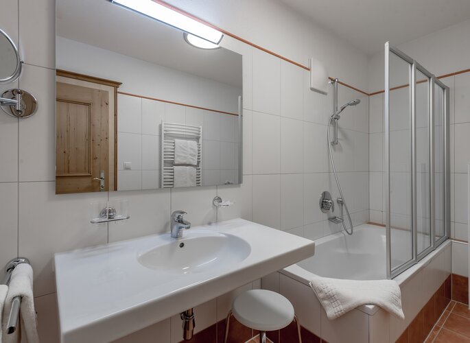 Badezimmer im Appartement in Obergurgl Modernes Badezimmer mit Waschbecken, Badewanne und Glasduschkabine im Appartement.
