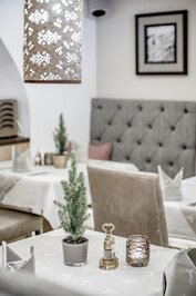 Ein gedeckter Tisch im Hotelrestaurant mit kleiner Tanne, Servietten und Tischaccessoires.