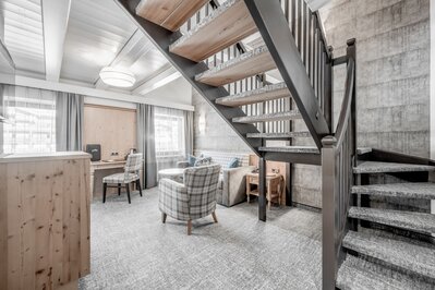 Ein modernes Maisonette-Zimmer mit Treppe, Sitzbereich, Schreibtisch und hellem Interior.