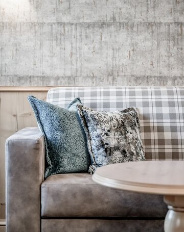 Ein Sofa mit gemusterten Kissen steht vor einer hellen, strukturierten Wand im Lounge-Bereich.