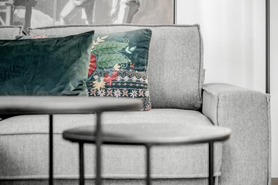 Eine gemütliche Sitzecke mit grauem Sofa und dekorativen Kissen in einem Hotelzimmer.