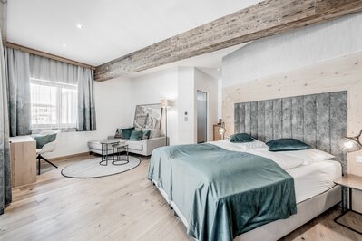 Modernes Hotelzimmer mit Doppelbett, Sitzbereich und großen Fenstern im Hotel Jenewein.
