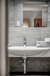 Ein modernes Waschbecken mit Spiegel und Ablage im Badezimmer eines Hotelzimmers.