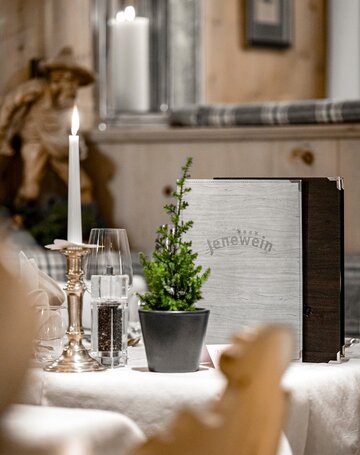 Ein gedeckter Restauranttisch mit Kerze, Glas und kleiner Topfpflanze im Hotel Jenewein.