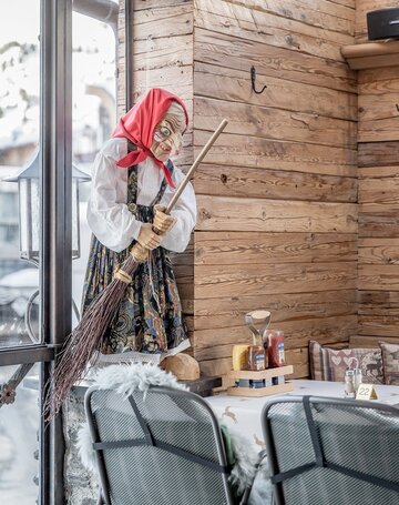 Eine Hexenfigur mit Besen steht in der holzverkleideten Terrasse des Hotels.