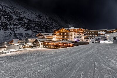 Das Hotel Jenewein liegt nachts an einem verschneiten Hang in Obergurgl.