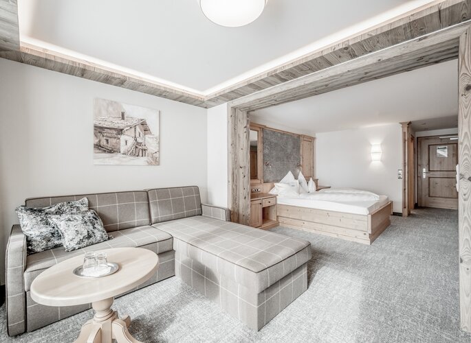 Juniorsuite im Hotel Jenewein in Obergurgl Helles Juniorsuite mit Sofa, Doppelbett und hellem Holzinterieur im Hotel Jenewein.