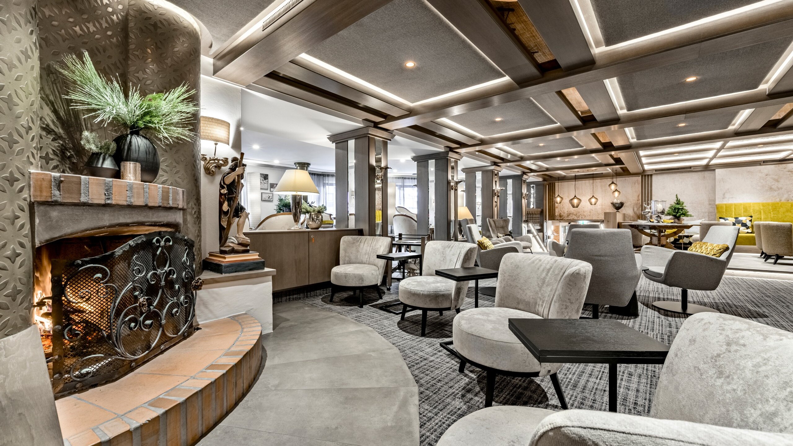 Eine stilvolle Hotel-Lounge mit Kamin, Sesseln und warmem Licht lädt zum Sitzen und Verweilen ein.