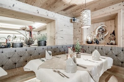 Ein stilvoll gedeckter Tisch in einem holzverkleideten Hotelrestaurant mit dekorierter Sitznische.