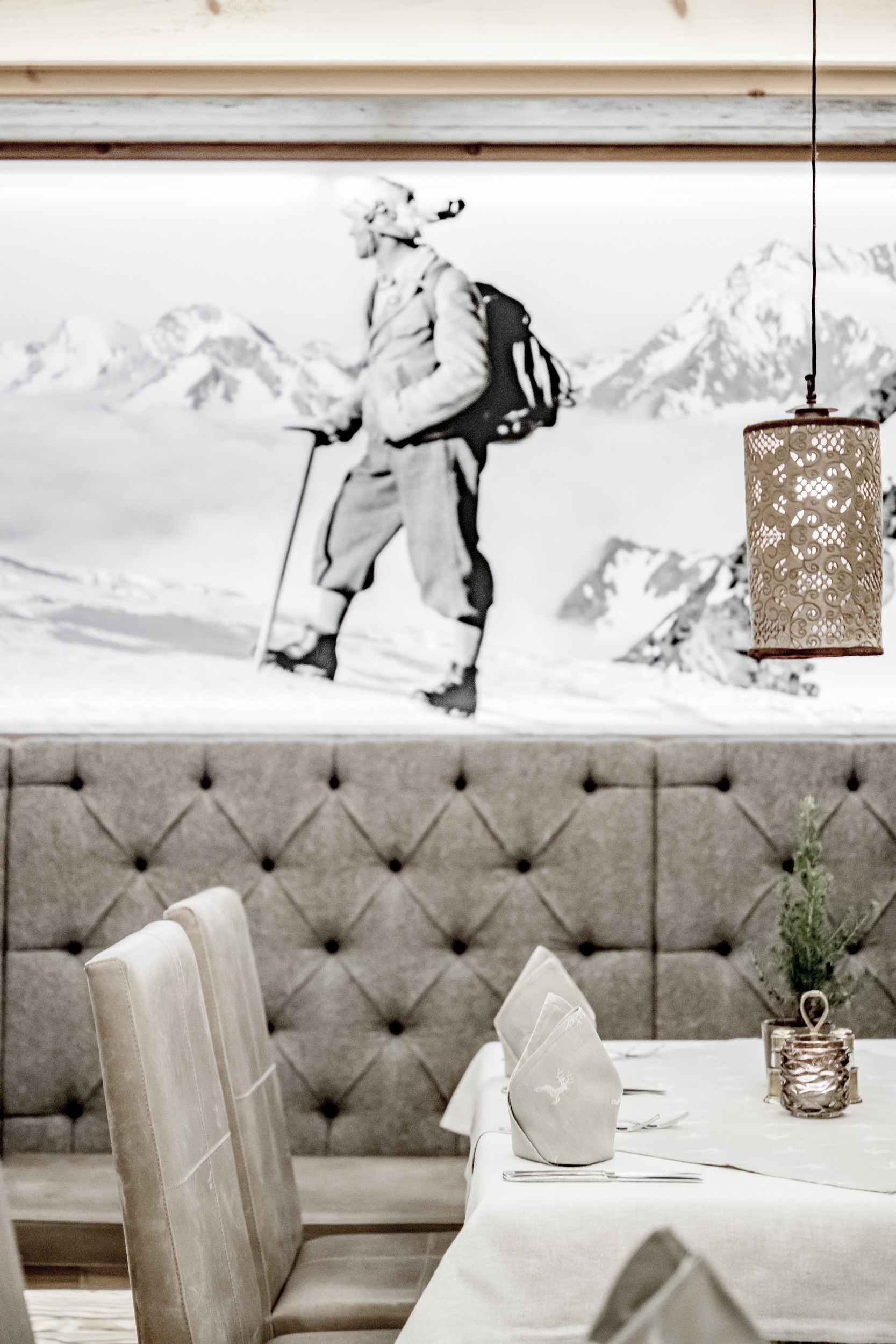 Ein gedeckter Tisch steht vor einer gepolsterten Sitzbank und einer Wand mit Bergmotiv.